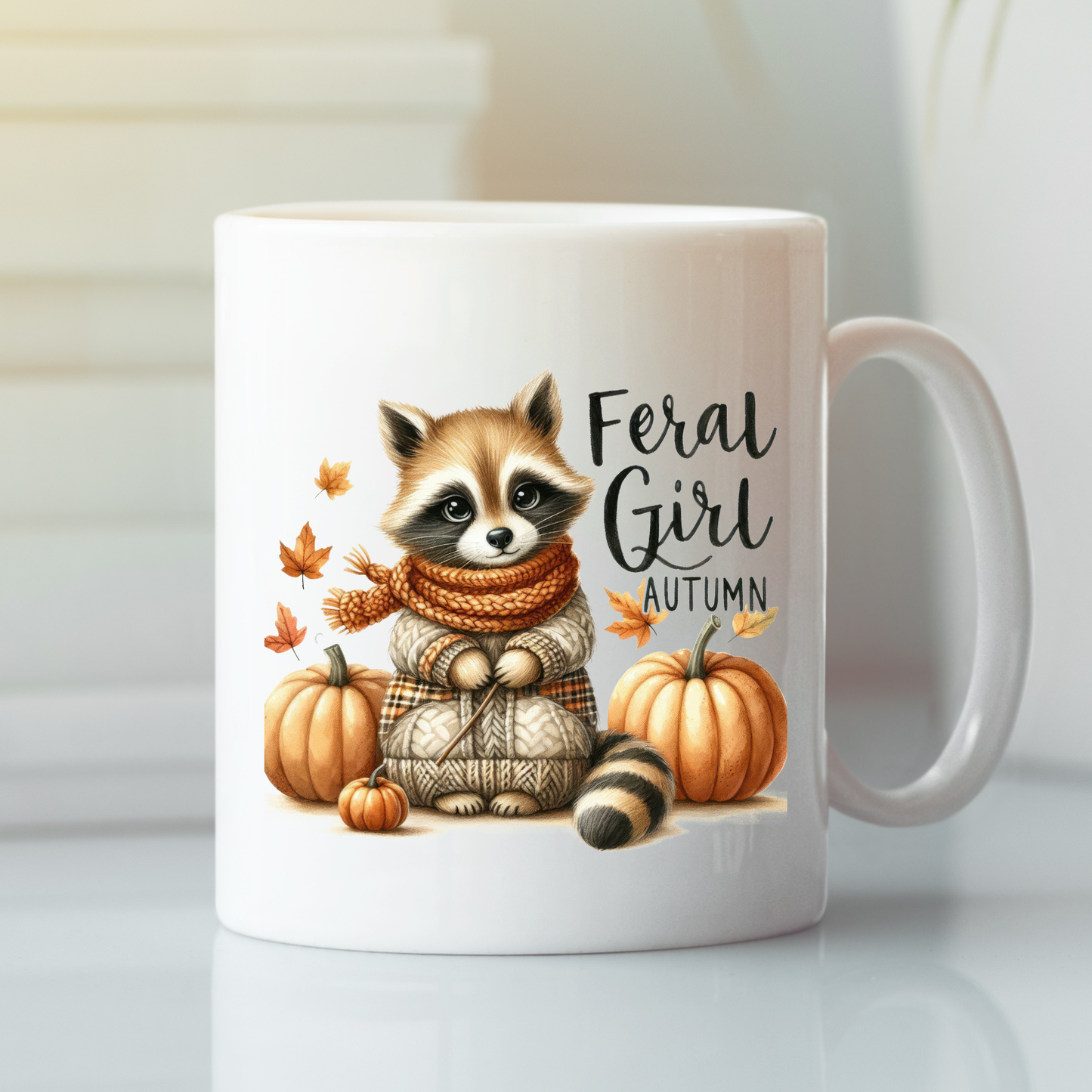 The Feral Girl Autumn Mug | Cozy Raccoon Fall Coffee Cup features a raccoon in a sweater and scarf with pumpkins and leaves, capturing the autumn vibe with "Feral Girl Autumn" text.