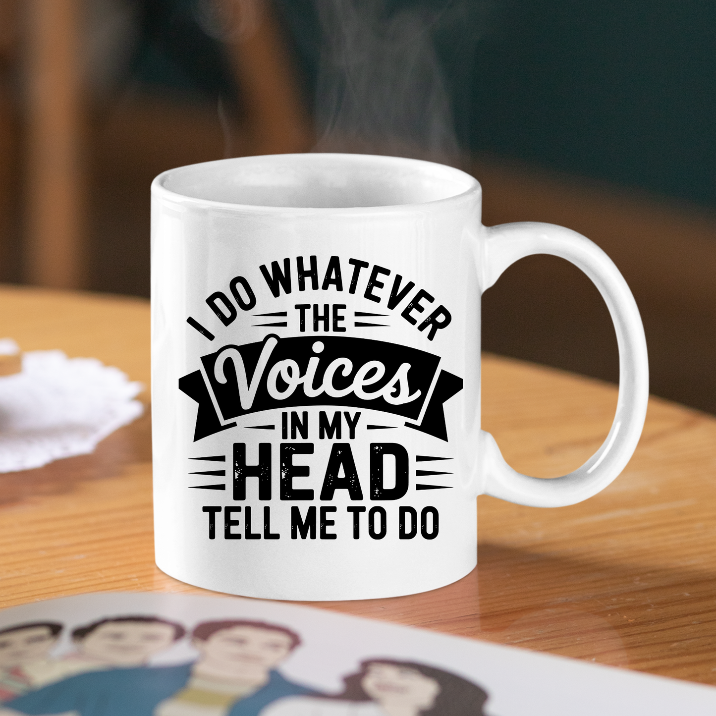 A white Voices in My Head Mug | Sarcastic Coffee Gift sits on a wooden table, featuring the bold black text: "I do whatever the voices in my head tell me to do." Hot steam rises from the mug, making it an ideal funny coffee mug and a perfect sarcastic gift for anyone who enjoys adding humor to their morning routine.