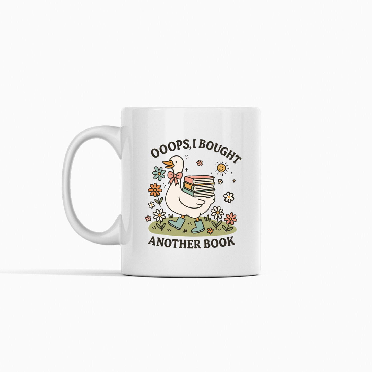 The Book Lover Mug | Ooops, I Bought Another Book Goose features a white mug with a goose holding books, flowers, and a sun. With the phrase "Ooops, I bought another book," it's the perfect whimsical gift for any book lover or bookworm.
