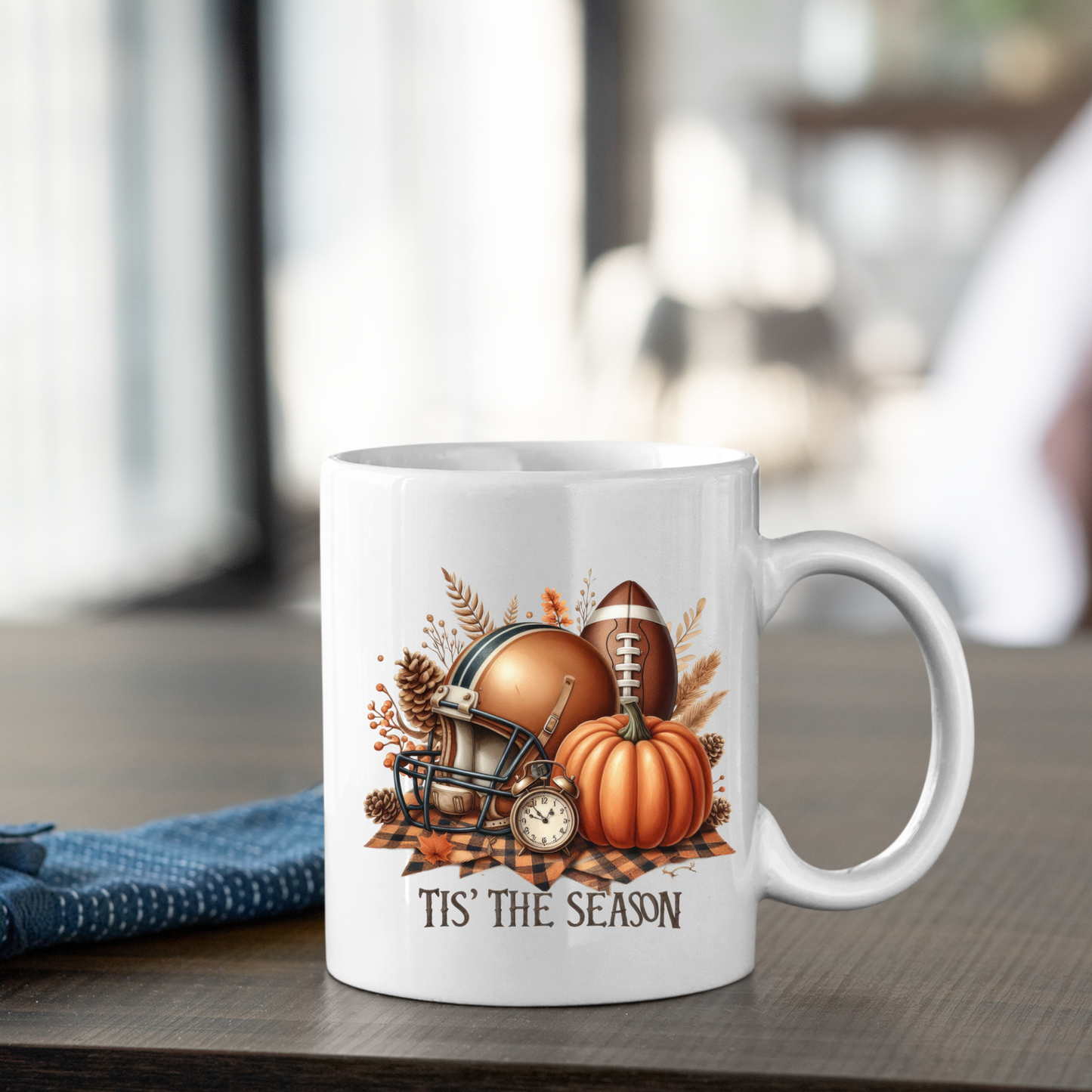 The Tis' the Season Football Mug features fall pumpkins, a football helmet, and autumn leaves with "TIS' THE SEASON" printed below—perfect for cozy game day vibes and any autumn coffee mug collection.
