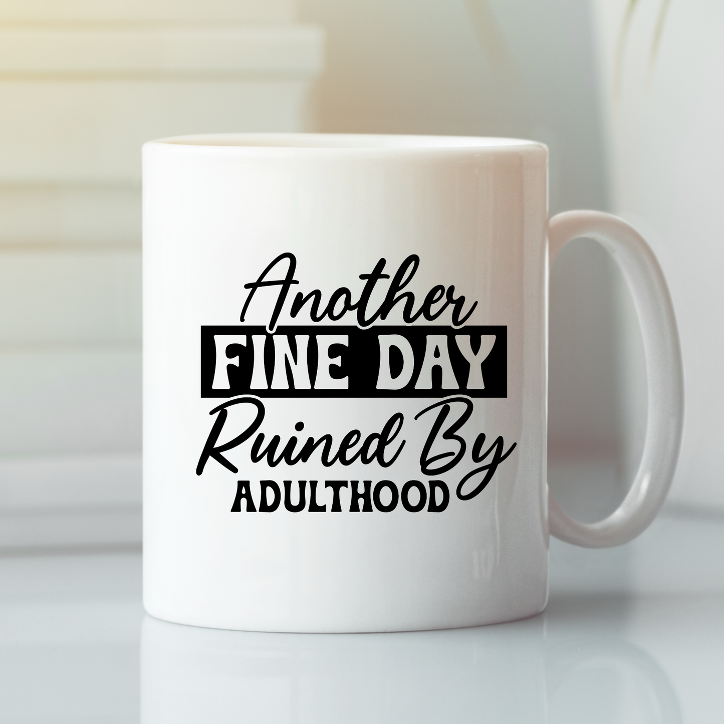 The "Another Fine Day Mug – Funny Adulthood Coffee Cup" features "Another fine day ruined by adulthood" with “fine day” in bold. This white mug is a perfect sarcastic gift for adults, photographed on a white surface in soft natural light.