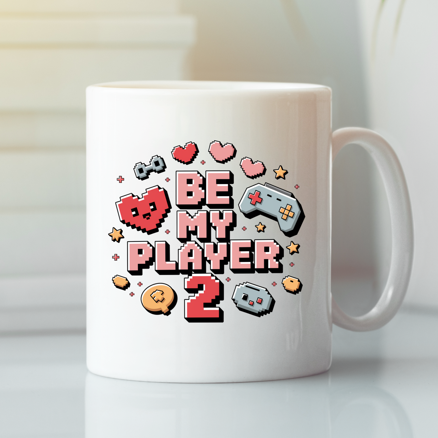 The Be My Player 2 Mug | Gamer Couple Gift features colorful pixel art hearts, game controllers, and retro video game-inspired "Be My Player 2" text on a classic white mug. Ideal as a gaming gift or player 2 mug for the special gamer in your life, it's showcased here on a white surface with a softly blurred background.