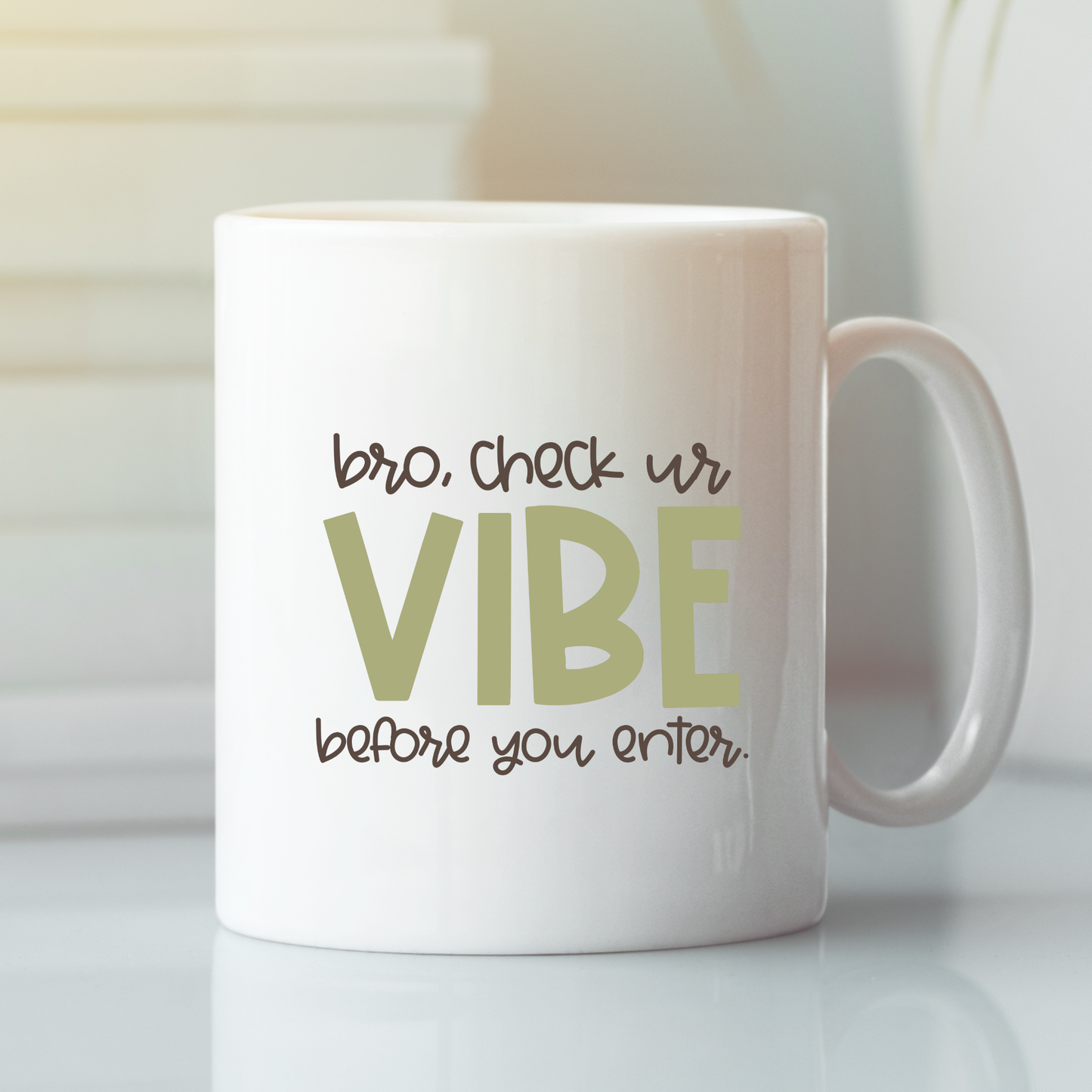 The Check Your Vibe Teacher Mug is a white mug with playful "bro, check ur VIBE before you enter." text—an ideal funny classroom gift for teachers. Shown on a light surface beside books, it's perfect for bringing humor to class.