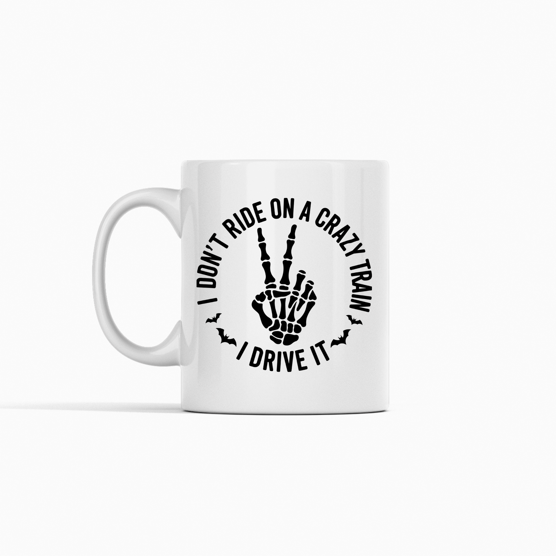 Show off your love for chaos in style with the Crazy Train Mug | Chaos Coffee Cup for Daily Mayhem—a white mug featuring bold black text that reads, "I DON'T RIDE ON A CRAZY TRAIN I DRIVE IT," wrapped around an edgy skeleton hand throwing the rock gesture, flanked by little bat silhouettes. It’s the ideal dark humor coffee cup for anyone who enjoys mayhem (and sarcasm) first thing in the morning.