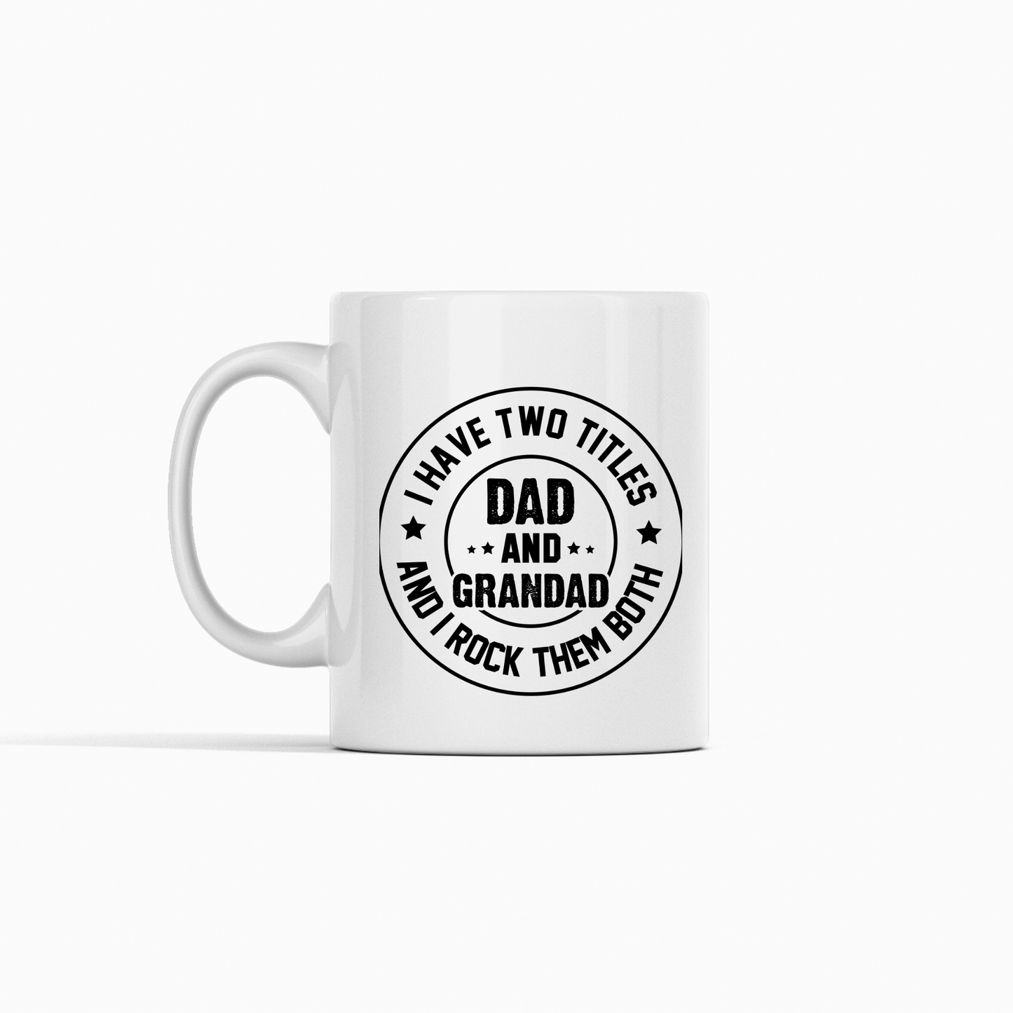 The Dad and Grandad Mug | Gift for Proud Grandad is a white ceramic coffee mug featuring a circular black design with the words, "I have two titles, Dad and Grandad, and I rock them both," accented by small stars. This stylish mug makes a thoughtful Father's Day gift for proud grandads and dads alike.