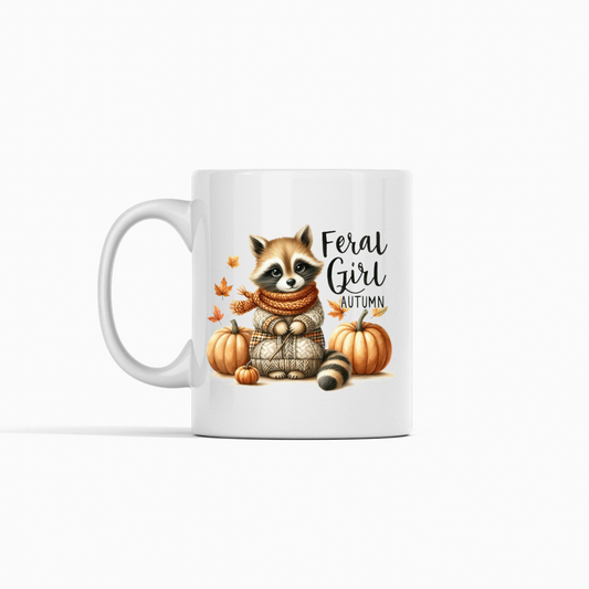 The Feral Girl Autumn Mug is a cozy fall coffee cup featuring a raccoon in a scarf and sweater among pumpkins and leaves, with “Feral Girl Autumn” text. Perfect for autumn vibes!.