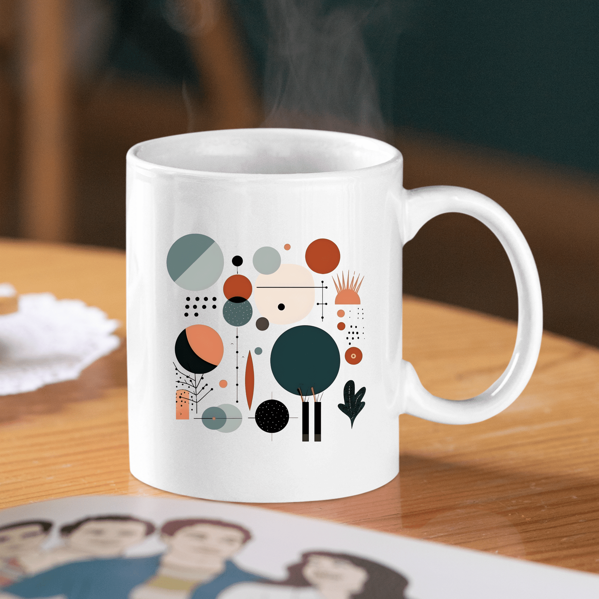 The Harvest Sun Mid Century Modern Mug, with an abstract geometric pattern in teal, orange, black, and beige, sits on a wooden table next to art. Steam gently rises from the stylish mug.