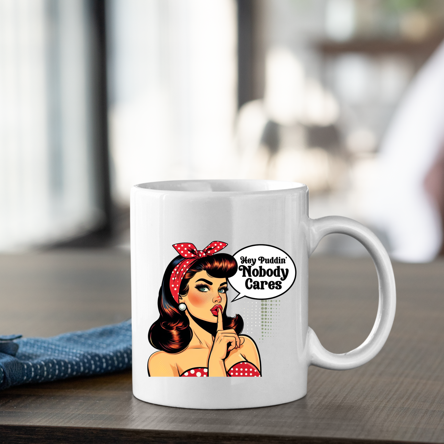 The Hey Puddin’ Nobody Cares Mug | Retro Pop Art Funny Gift features a woman with red lipstick and a polka-dot headband, holding a finger to her lips by a speech bubble saying, “Hey Puddin’ Nobody Cares”—the perfect funny mug or sarcastic gift.