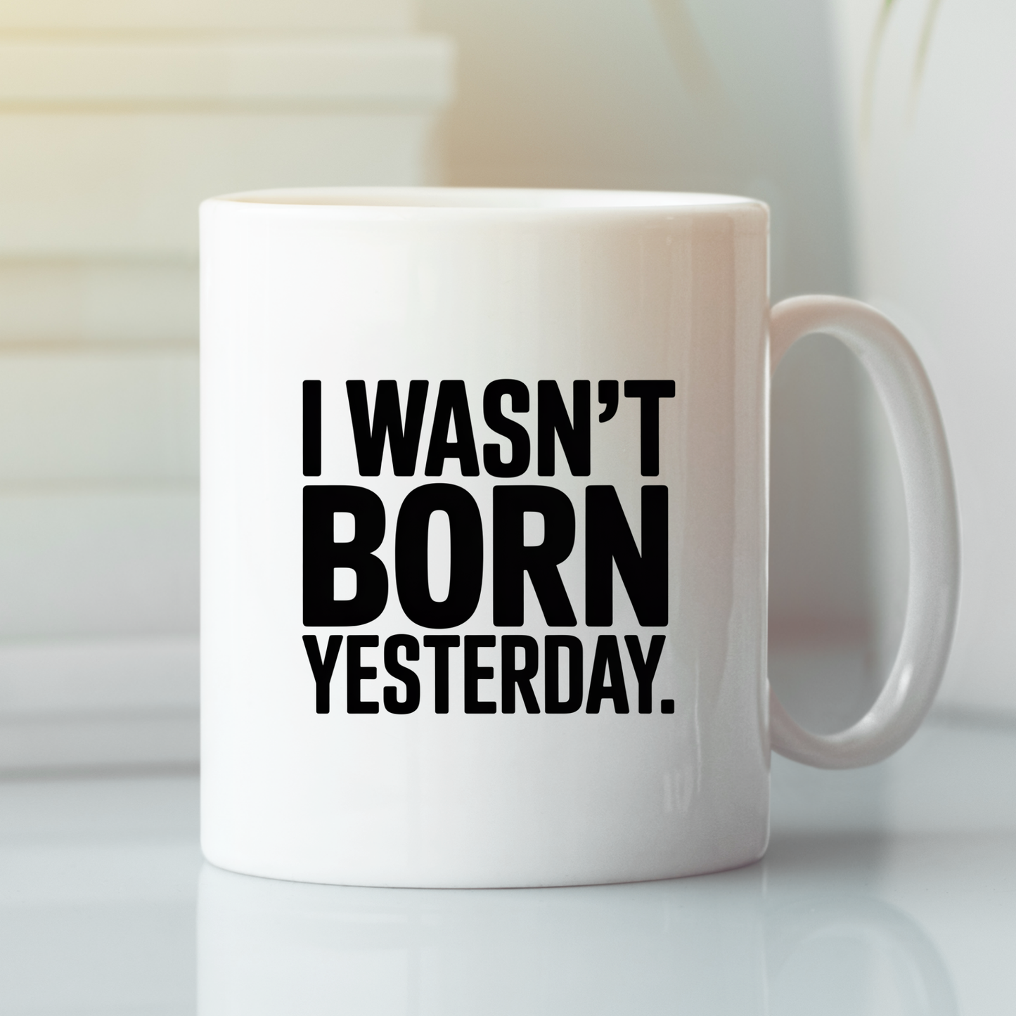 Introducing the I Wasn't Born Yesterday Mug | Witty Quote Coffee Cup—a humorous ceramic mug featuring bold black text declaring, "I WASN'T BORN YESTERDAY." Set atop a reflective surface with a softly blurred background, this sarcastic coffee cup is ideal for those who appreciate clever sayings with their daily coffee.