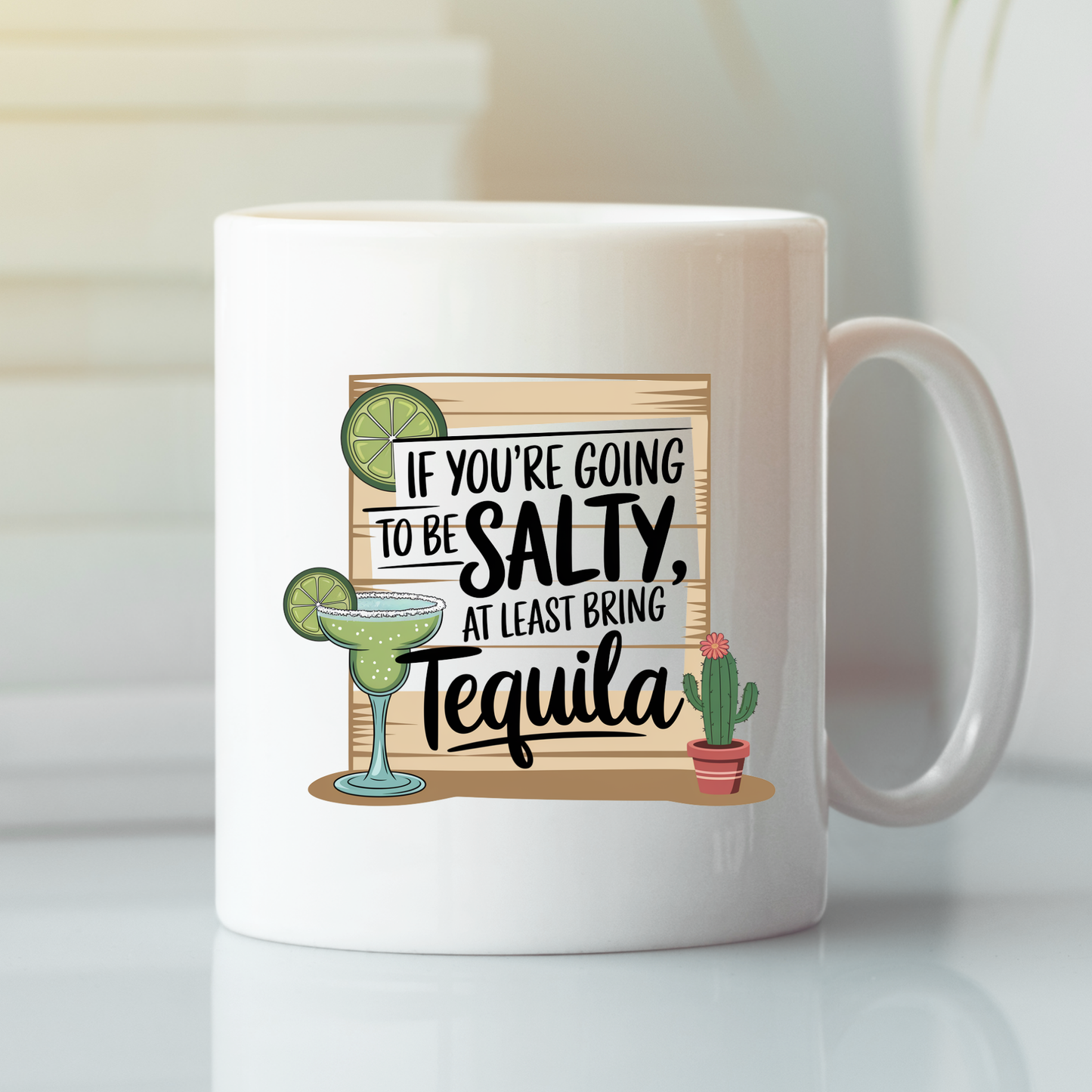 Enjoy a laugh with the If You're Going to Be Salty Bring Tequila Mug, a white margarita-themed mug featuring a fun illustration of a margarita glass, lime, and small cactus alongside the clever phrase "If you're going to be salty, at least bring tequila." This humorous coffee mug is the perfect gift for tequila lovers and anyone who appreciates combining wit with their favorite drinks.