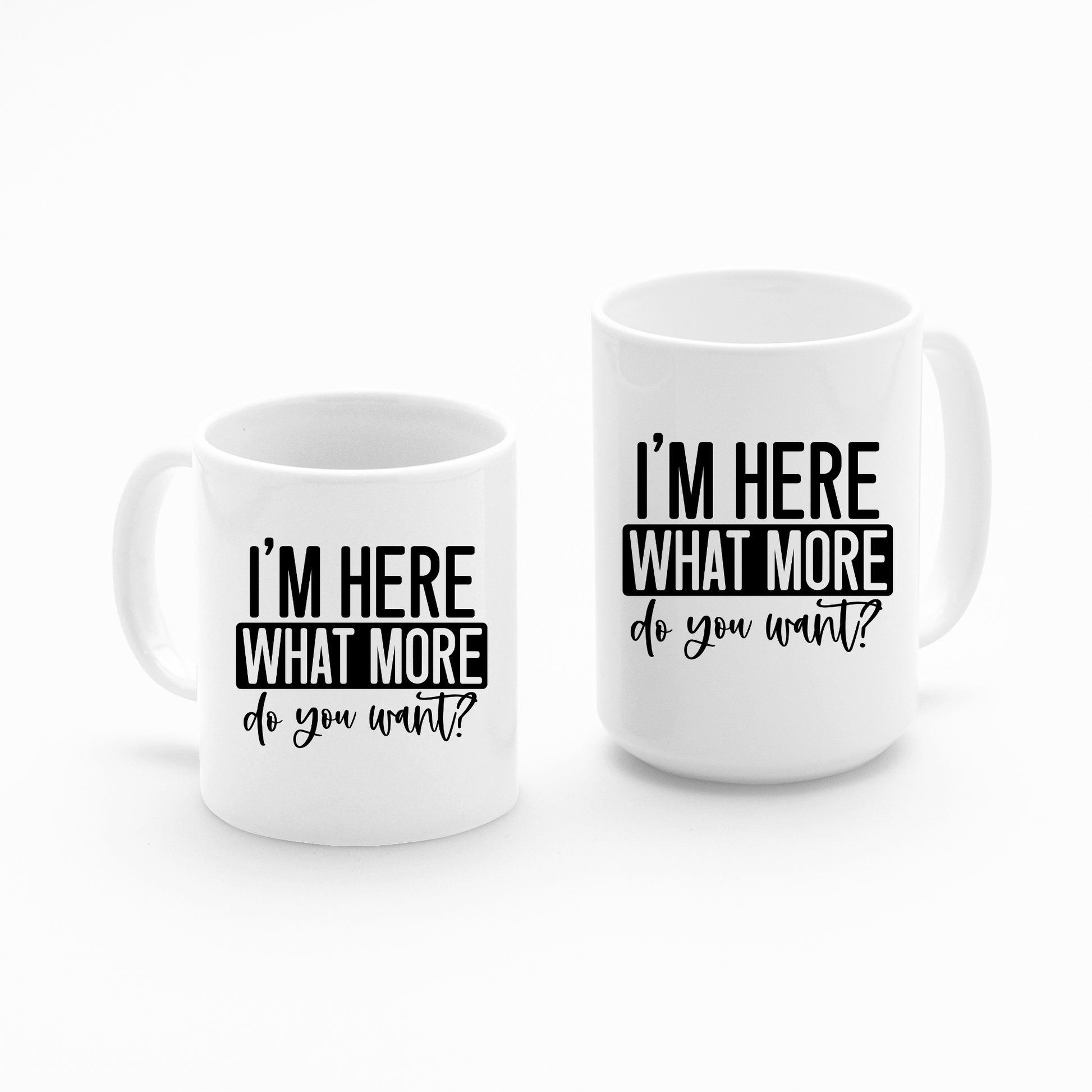 The "I’m Here What More Do You Want Mug | Funny Sarcastic Coffee Cup" features two white mugs with black text—one tall, one short—side by side. Ideal for the office or as a witty introvert gift.