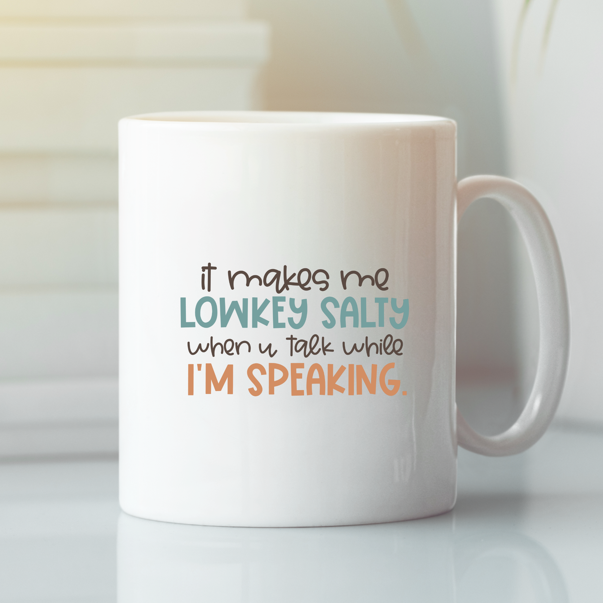 The Lowkey Salty Teacher Mug | Funny Classroom Humor is a white ceramic mug featuring “it makes me LOWKEY SALTY when u talk while I'M SPEAKING.” in black, teal, and orange—ideal for classroom laughs or as a teacher appreciation gift.