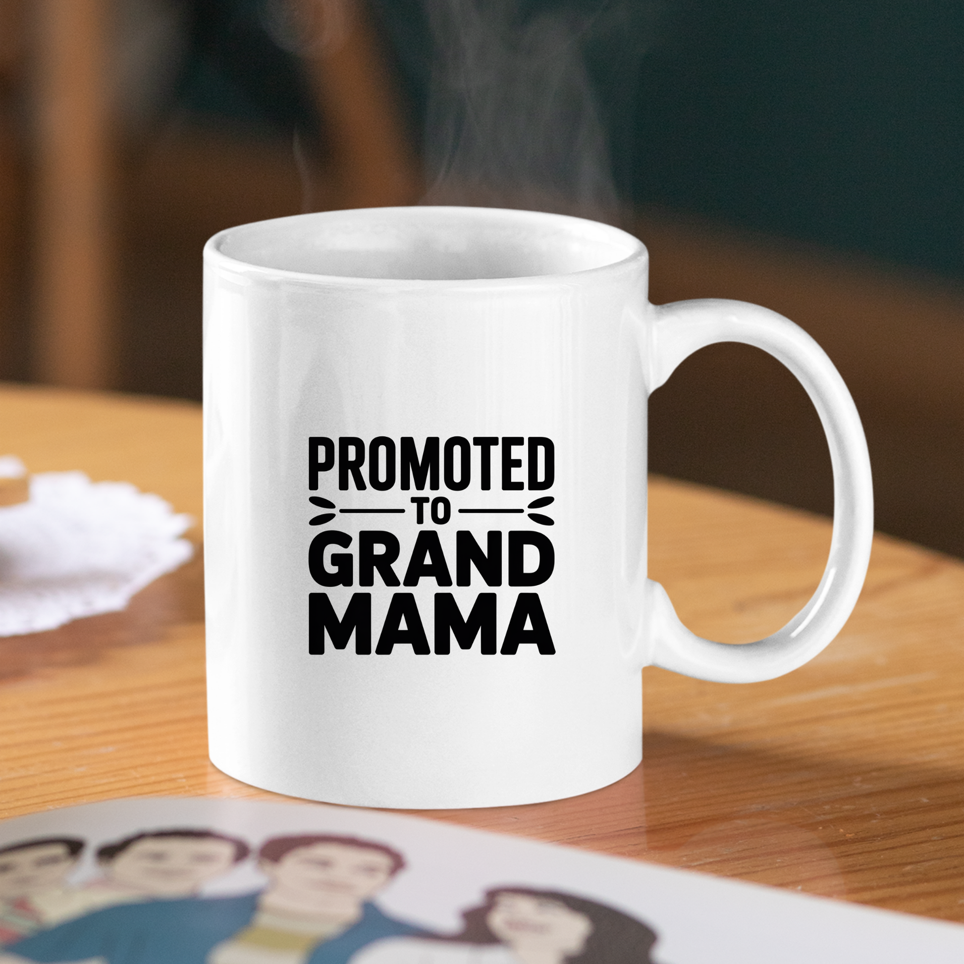 A white Promoted to Grand Mama Mug | New Grandma Gift rests on a wooden table with the phrase "Promoted to Grand Mama" boldly printed in black lettering while steam curls up from its rim. This delightful pregnancy announcement mug is the perfect way to celebrate a new grandma and mark this special milestone with every sip.