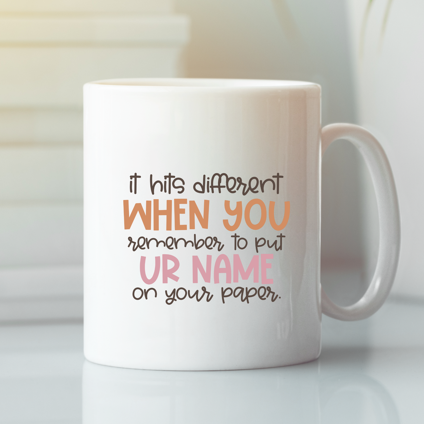 The "Put Your Name On Your Paper Mug | Funny Teacher Gift" features playful text: "it hits different WHEN YOU remember to put UR NAME on your paper." A humorous mug for teachers, perfect for classroom laughs and gifting.