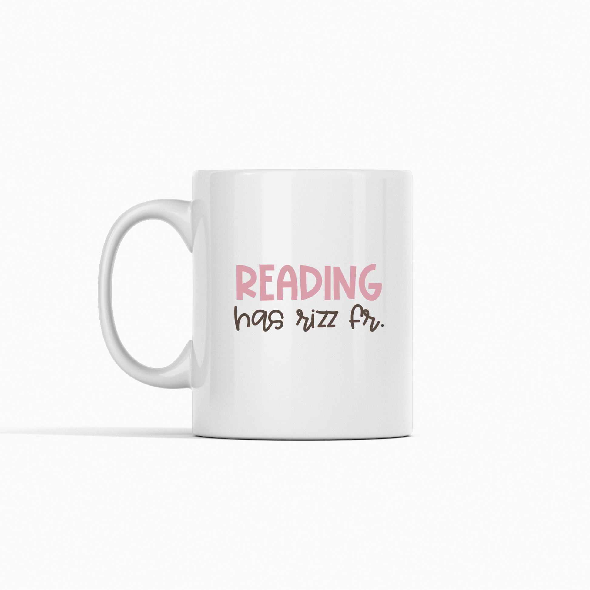 The Reading Has Rizz Mug | Funny Literacy Teacher Gift features "READING" in pink caps and "has rizz fr." in black cursive on white ceramic, making it a playful pick for book lovers or teacher gifts. Set on a plain white background.