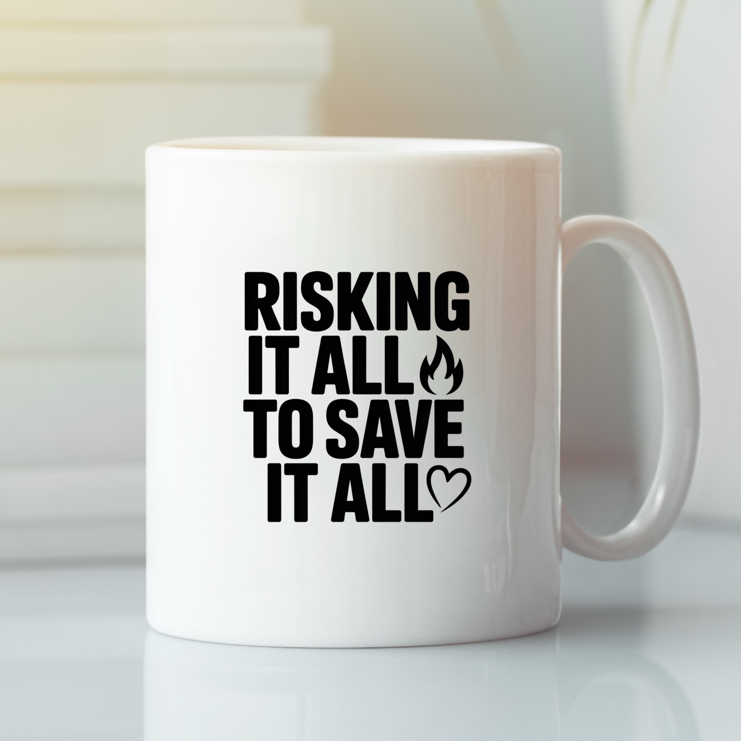 The “Risking It All to Save It All Firefighter Mug” is a white mug featuring bold black lettering that reads: "RISKING IT ALL TO SAVE IT ALL," with a small flame icon above the word "SAVE" and a heart icon beneath "ALL." Ideal as a firefighter gift, this mug pays daily tribute to the courage of those who risk everything for others.