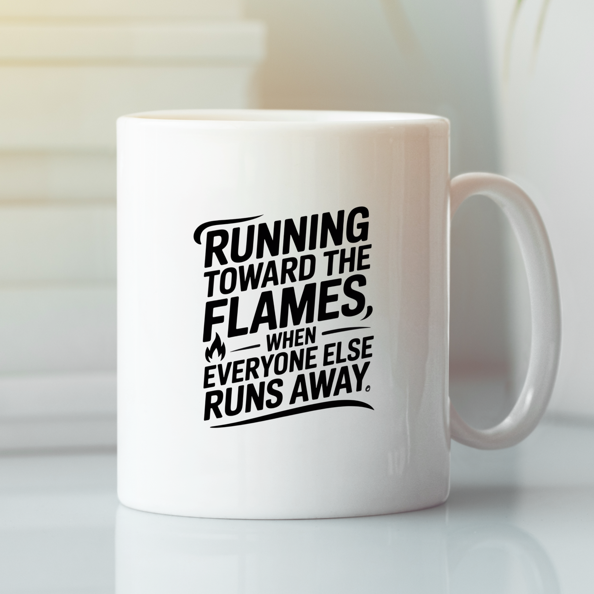 The Running Toward the Flames Firefighter Mug features black text on a white ceramic mug that reads, “Running toward the flames, when everyone else runs away.” Displayed on a white surface with softly blurred background details, this courage-themed coffee mug makes an ideal firefighter gift.