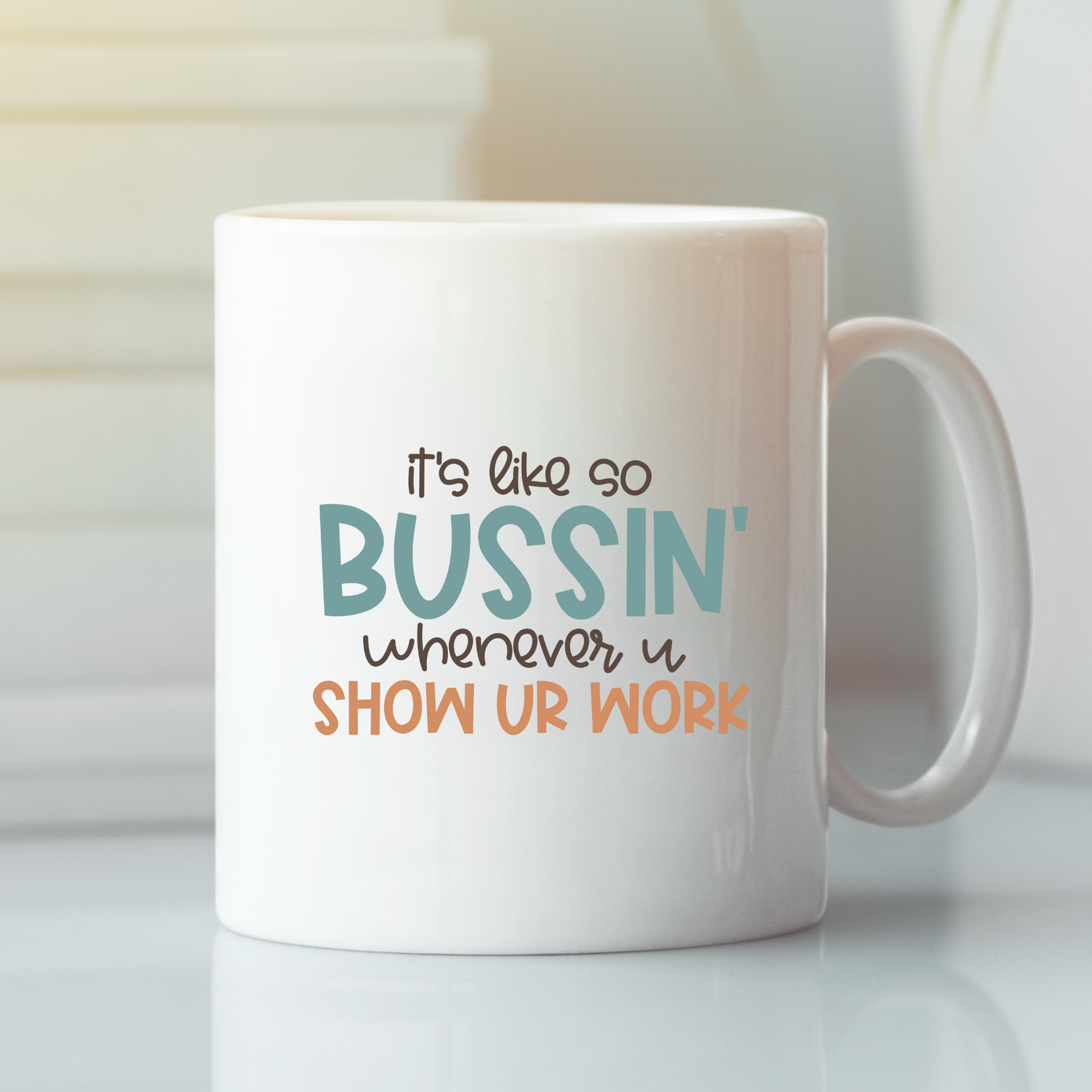The Show Your Work Teacher Mug | Funny Math Teacher Gift features "It's like so BUSSIN' whenever u SHOW UR WORK" in playful blue, black, and orange fonts. Perfect for teacher appreciation gifts! The white mug is pictured on a light surface.