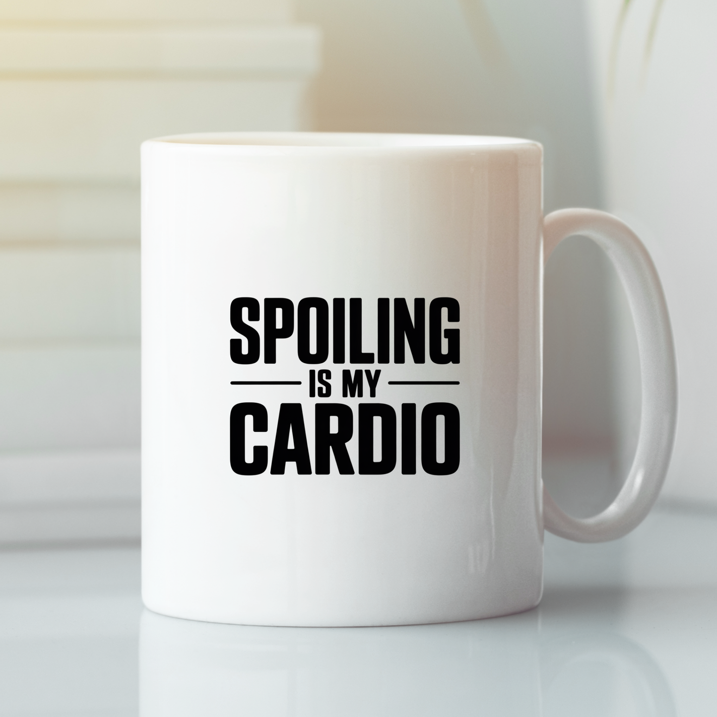 The "Spoiling Is My Cardio Mug | Funny Grandparent Gift" is a white ceramic mug featuring bold black text that reads, "Spoiling is my cardio." Shown on a clean white surface with softly blurred background accents, it’s the ideal present for grandparents who proudly spoil their grandkids.