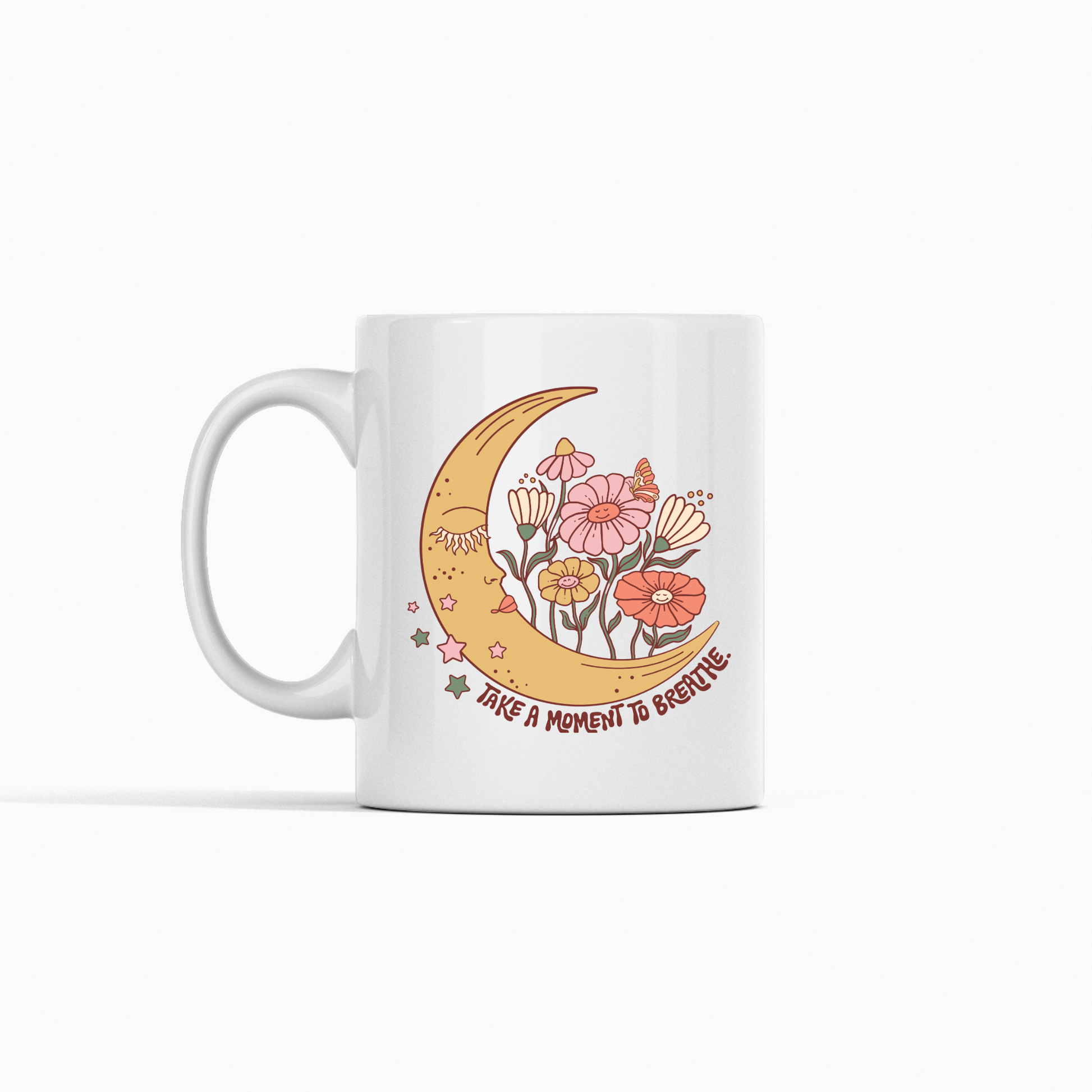 The Take a Moment to Breathe Mug | Mindfulness Coffee Mug features a yellow crescent moon, colorful flowers, and twinkling stars on a classic white background. Accented with pastel pink, orange, and green details, this whimsical mug includes the inspirational message "Take a moment to breathe," making it an ideal meditation mug or thoughtful self-care gift.