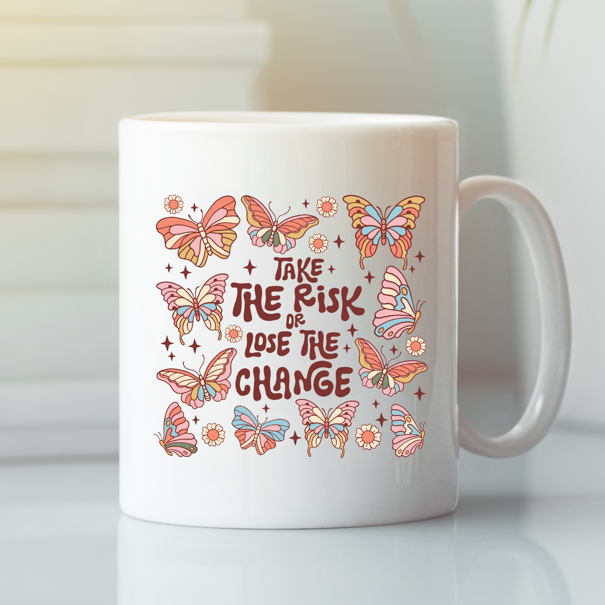 The "Take the Risk or Lose the Change Mug | Inspirational Coffee Mug" features a white background decorated with vibrant butterflies and flowers surrounding the bold phrase "Take the risk or lose the chance" in playful lettering—making it a perfect gift for celebrating new beginnings.