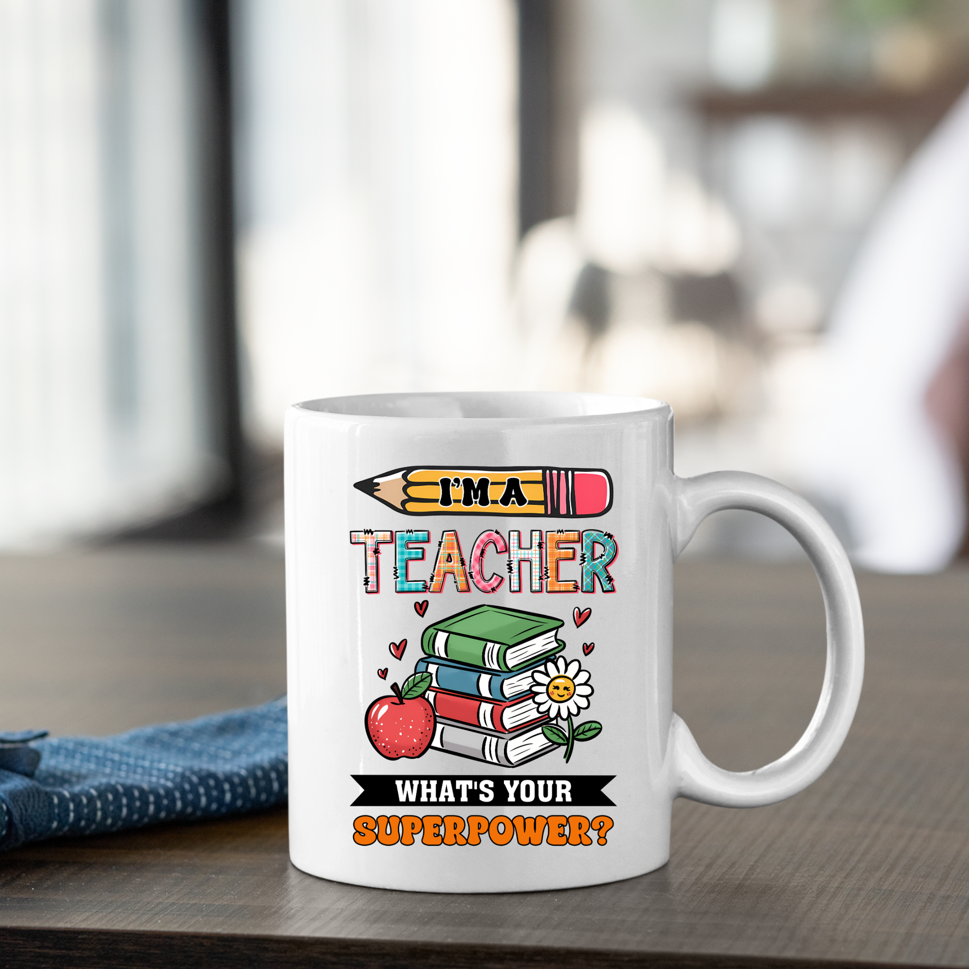 The “I’m a Teacher, What’s Your Superpower Mug | Fun Teacher Gift Idea” is a white mug decorated with colorful pencils, books, an apple, flowers, and hearts—perfect for showing teacher appreciation. A blue napkin rests beside it.