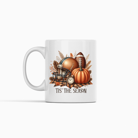 Sip in style with the Tis' the Season Football Mug, featuring football, helmet, pumpkins, autumn leaves, and a small clock—perfect for cozy fall game days!.